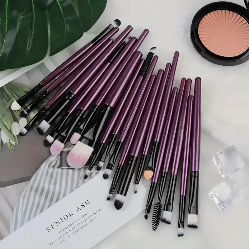 A set of purple makeup brushes arranged on a surface with a makeup compact and ice cubes.