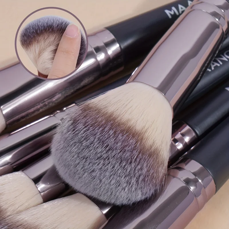 Close-up view of a set of makeup brushes with metallic rose gold handles and fluffy bristles. The brushes are arranged in a pile, showcasing their soft texture and luxurious look.