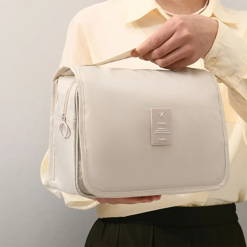 A person holding a beige travel bag.