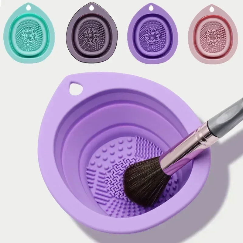 A purple silicone makeup brush cleaning bowl with a makeup brush inside. Three other silicone bowls in different colors are shown in the background.