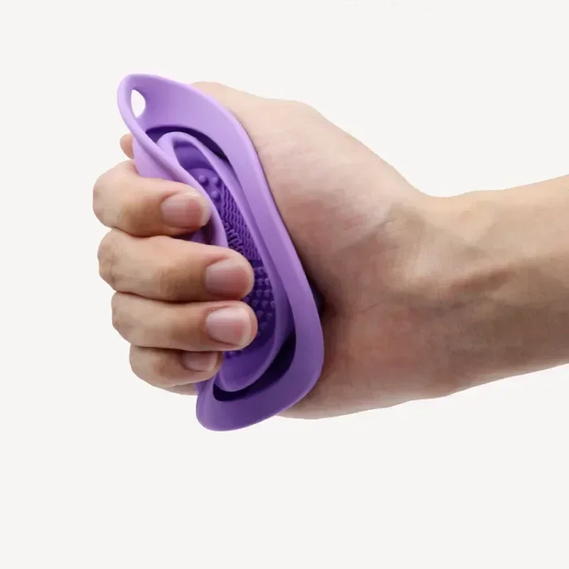 A hand holding a purple silicone bath scrubber.