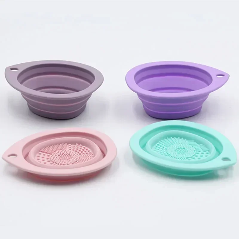 Four collapsible silicone bowls in different pastel colors are shown on a white surface. Two of the bowls have a built-in silicone brush.