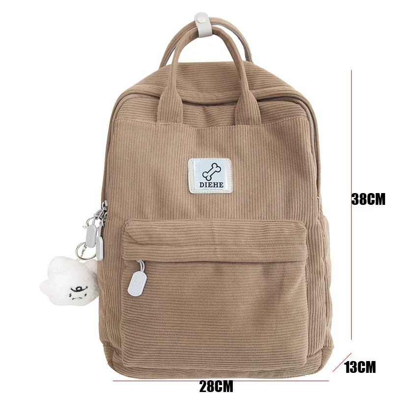 A light brown corduroy backpack with a small bone-shaped logo and a fluffy white cloud keychain.