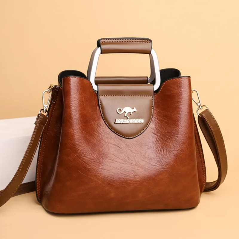 A brown leather handbag with a silver top handle and a kangaroo logo.