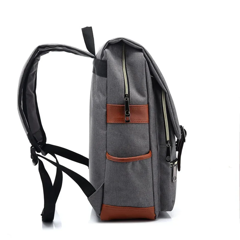 Side view of a gray canvas backpack with brown leather accents. The backpack is standing upright and shows its side profile, highlighting its straps, zippers, and pockets.