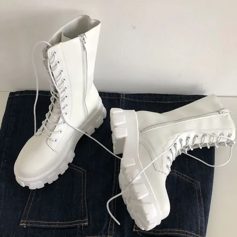 A pair of white platform lace-up boots on a denim background.