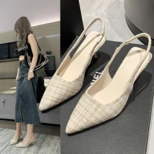 A pair of beige slingback heels with a pointed toe and a low heel. The heels are made of a tweed-like fabric. A woman is wearing a pair of the same shoes.