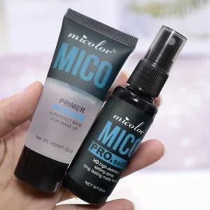 Close-up view of a hand holding two MICO brand makeup products: a primer tube and a setting spray bottle. Both products feature a sleek black and blue design.