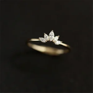 A delicate gold ring adorned with five marquise-cut diamonds, arranged in a crown-like formation atop the band. The ring is elegantly displayed against a stark black background, enhancing its subtle brilliance.