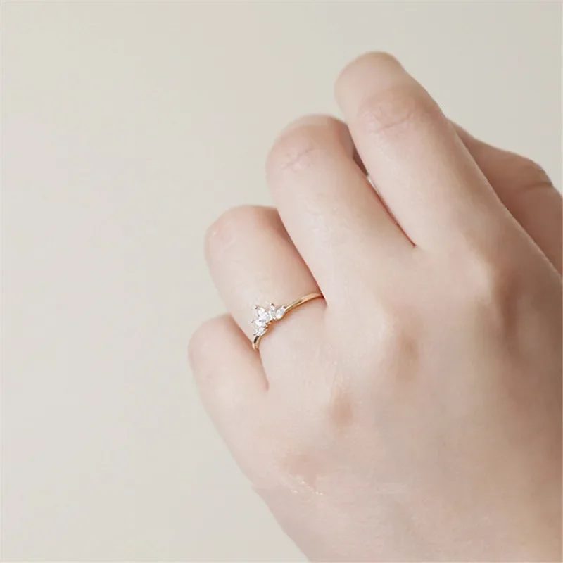 Close-up of a woman's hand wearing a delicate gold ring with small, sparkling stones.