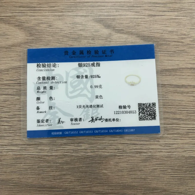 A close-up shot of a certificate for a silver ring. The certificate is in Chinese and English, and it shows that the ring is made of 925 sterling silver and weighs 0.99 grams. The certificate also includes a QR code and a testing number.