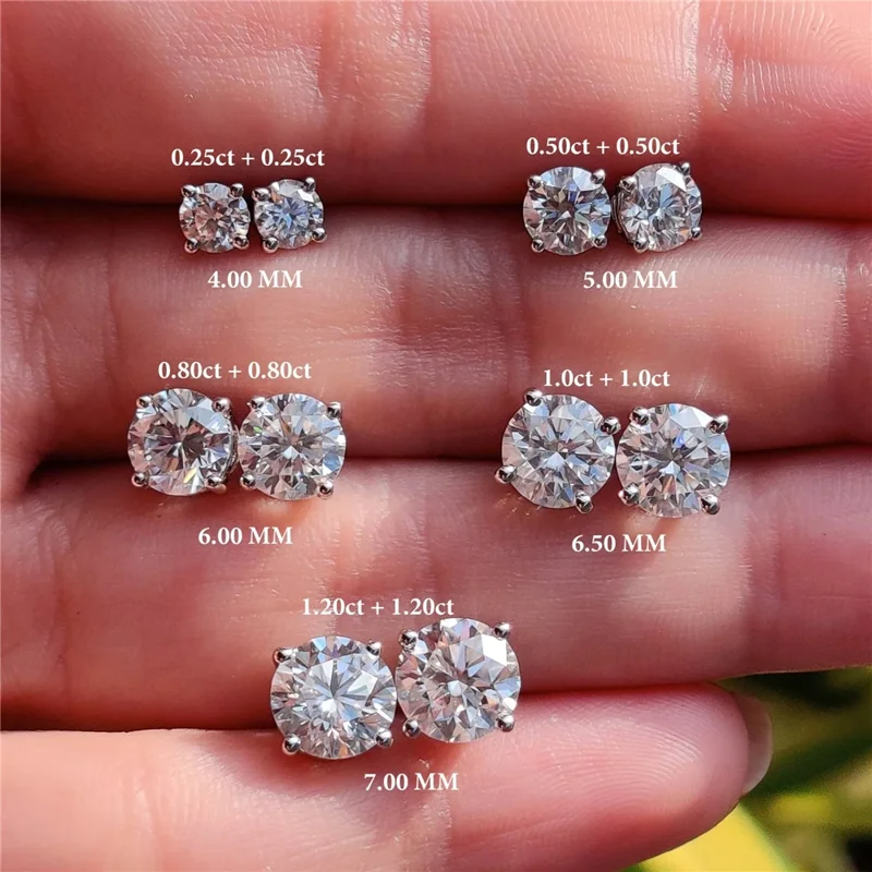 Close-up image showcasing a collection of diamond stud earrings of varying carat weights and sizes, arranged on a hand for comparison. Each pair is labeled with its carat weight and diameter in millimeters.