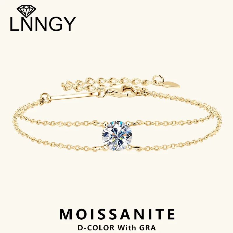 A gold bracelet with a single, round, clear gemstone in the center. The bracelet has a delicate chain design.