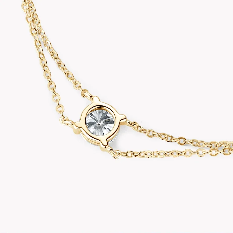 Close-up of a delicate gold necklace with a single, clear gemstone pendant.