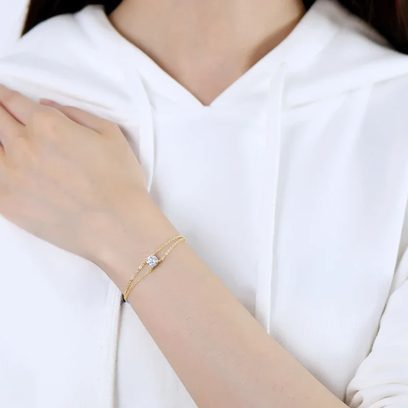 Close-up of a woman's wrist wearing a delicate gold bracelet with a single, sparkling diamond.