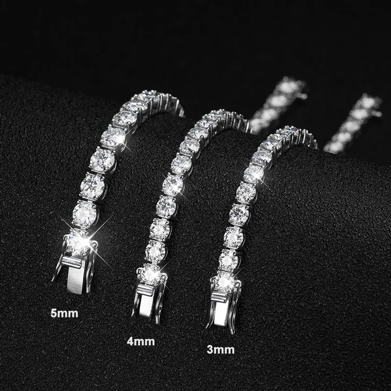 Three tennis bracelets of different widths (3mm, 4mm, and 5mm) are displayed on a dark surface. Each bracelet is adorned with sparkling, round-cut stones, creating a luxurious look. The bracelets are neatly arranged, showing the size variation clearly. The image is sharply focused and well-lit, highlighting the brilliance of the stones and the quality of the bracelets.
