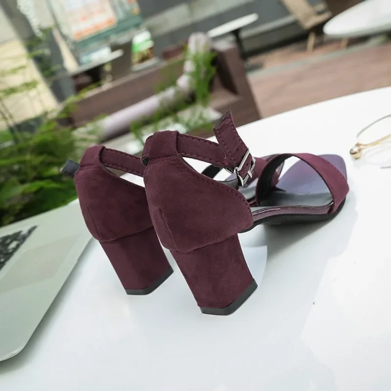 A pair of burgundy suede heeled sandals with ankle straps.
