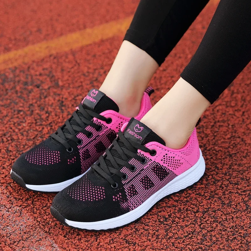 A pair of black and pink sneakers with white soles. The sneakers are knit and have a logo on the tongue.