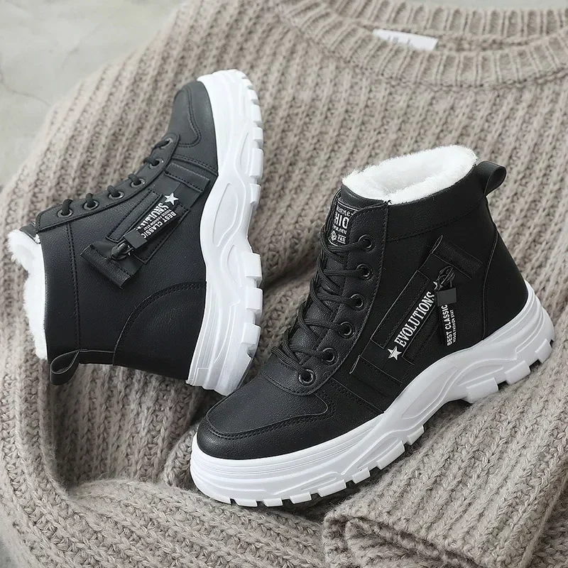 A pair of black and white winter boots with white soles and fur lining sits on a gray sweater.