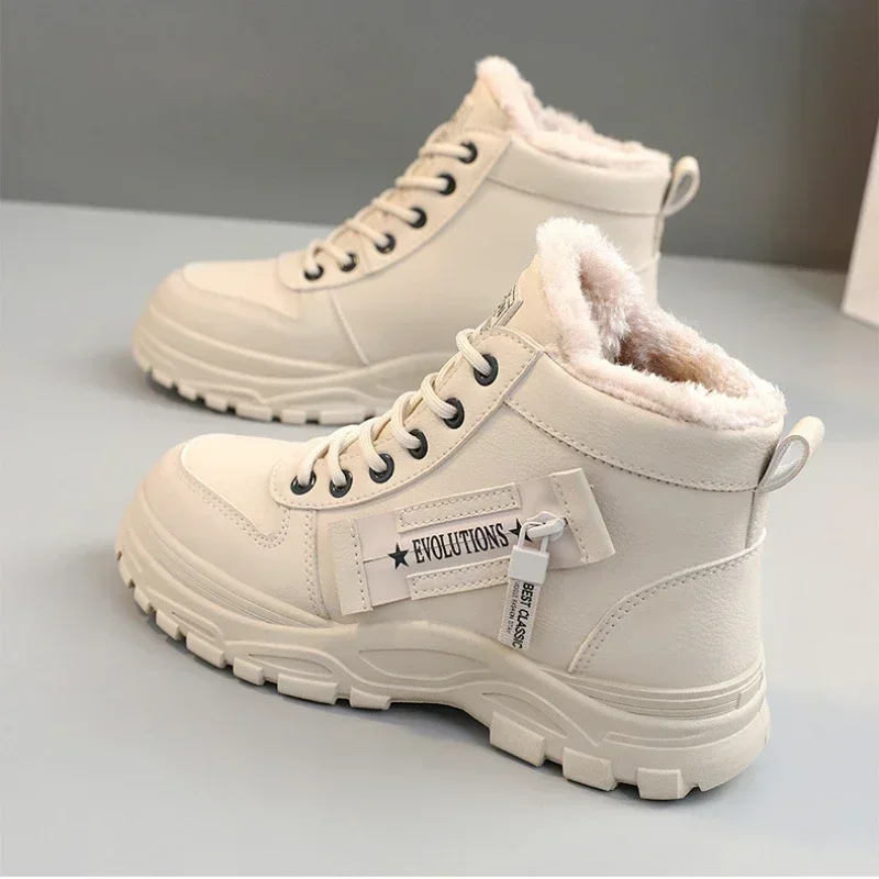 A pair of cream-colored ankle boots with faux fur lining sits on a gray surface. The boots have chunky soles and are laced up the front. A tag on the side of one boot reads "EVOLUTIONS" and "BEST CLASSIC."