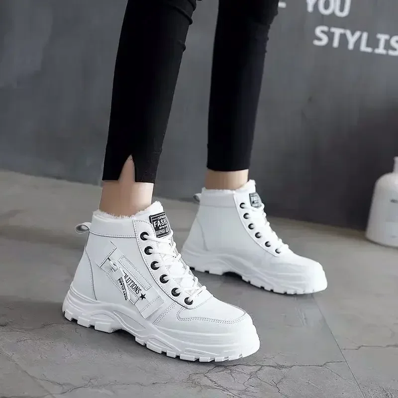 A pair of white high-top sneakers with black accents and a zipper detail. The shoes are worn by a model who is wearing black leggings.