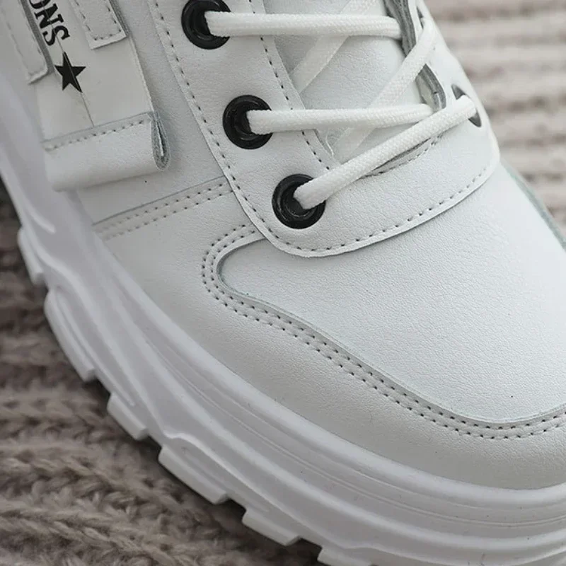 Close-up of a white chunky sneaker with black accents and white laces. The sneaker has a thick sole and is made of leather. The brand name is partially visible on the side.