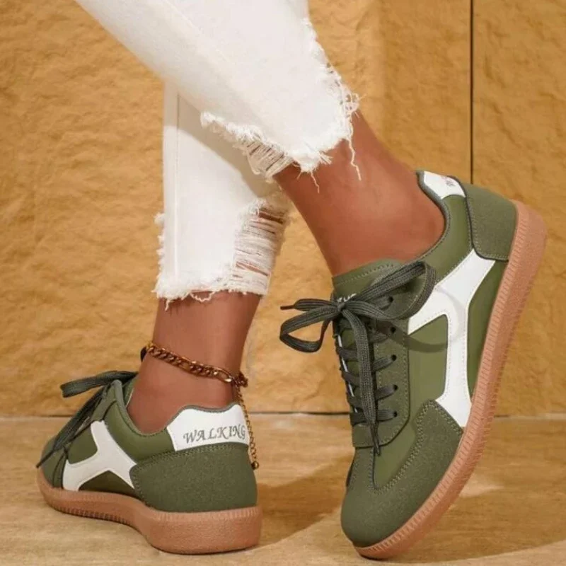 Close-up of a person's legs wearing a pair of olive green and white sneakers with distressed white jeans.