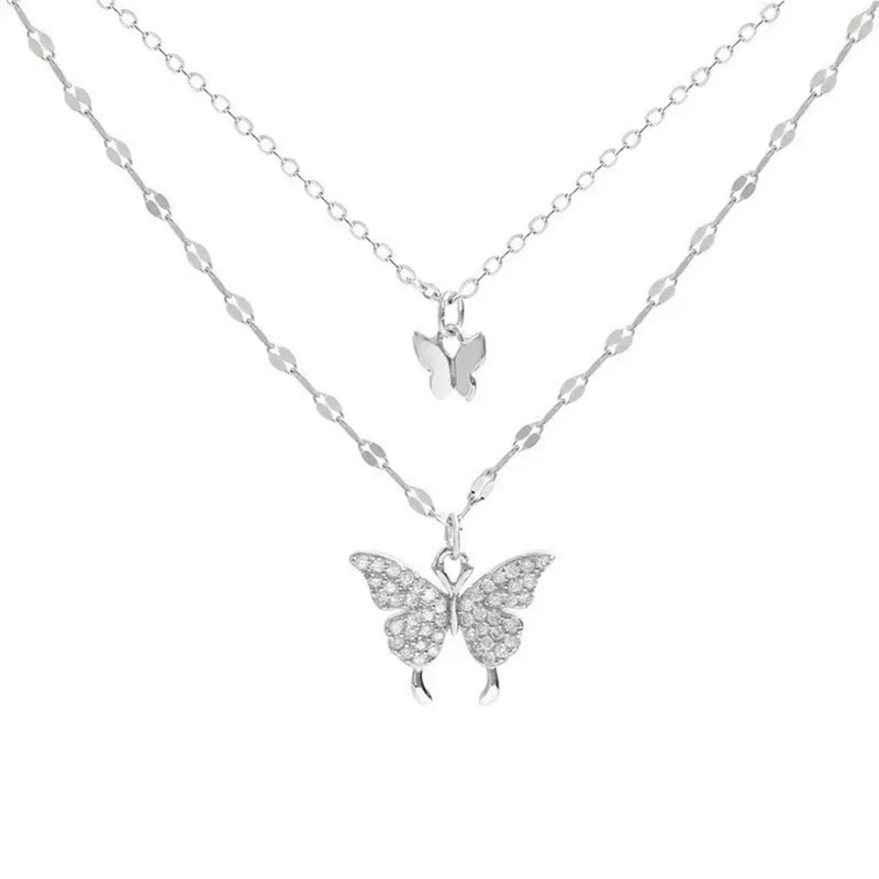 Double layered necklace with two butterfly pendants. The top pendant is a smaller, plain butterfly, while the bottom pendant is a larger butterfly encrusted with sparkling stones.
