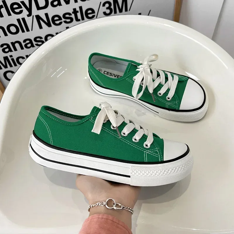 A pair of green canvas shoes with white soles and laces. The shoes are on a white surface.