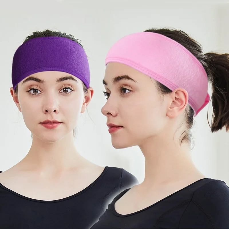 Two women are shown, each wearing a different colored headband. One headband is purple and the other is pink. Both headbands are made of soft, absorbent material and are perfect for keeping hair out of the face while cleansing or applying makeup.