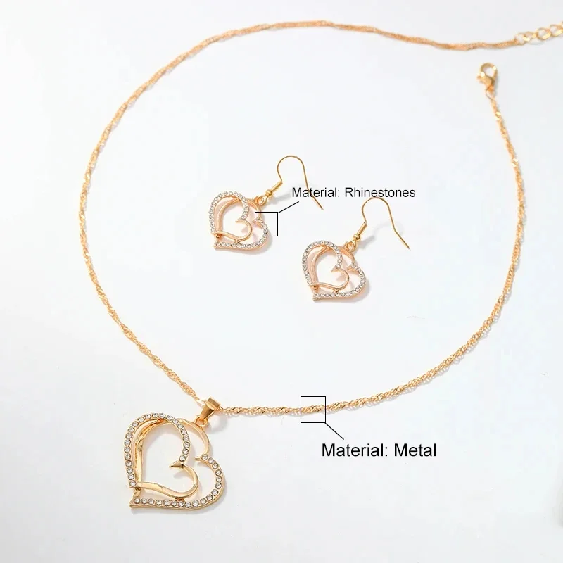 A gold necklace and earrings set with double heart pendants and earrings. The hearts are encrusted with rhinestones. The necklace and earrings are made of metal.