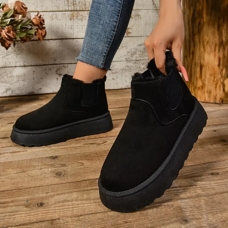 A person's legs and feet are shown wearing black ankle boots with thick soles and a fuzzy interior. The boots are stylish and appear warm and comfortable.