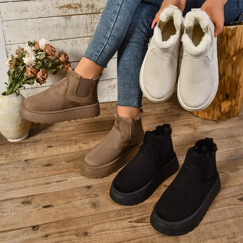 A person's legs and feet wearing four different pairs of ankle boots on a wooden floor. Two pairs are light beige, one pair is brown, and one pair is black. The boots all have a platform sole and a fuzzy interior.