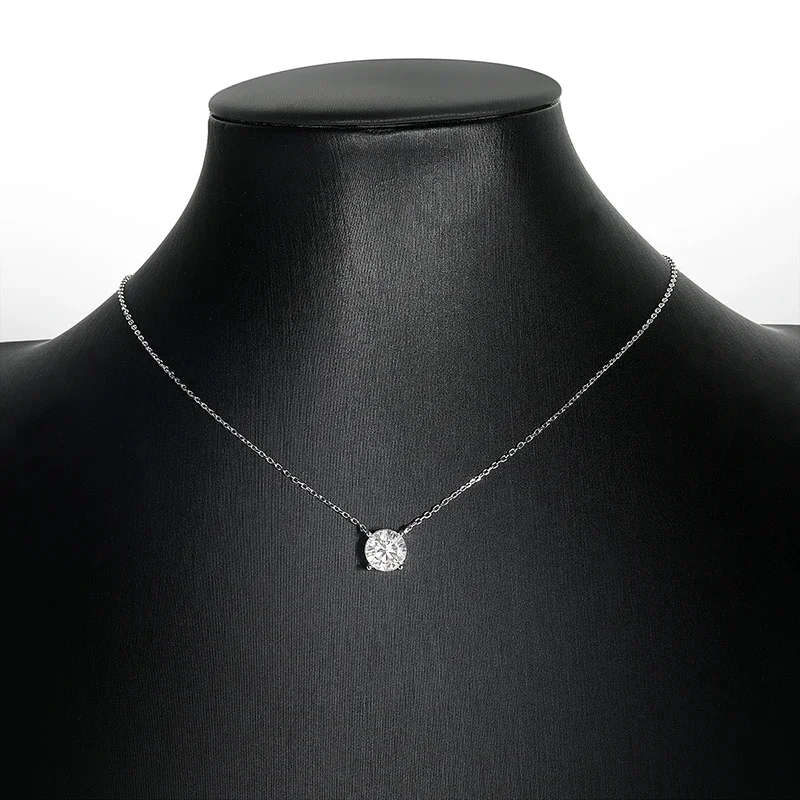 A silver necklace with a single, large, round diamond pendant rests on a black jewelry display stand.