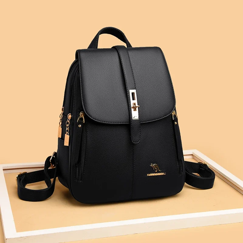 A black leather backpack with gold accents sits on a white frame against a beige background.
