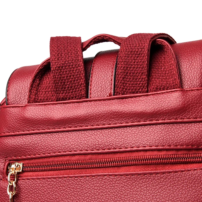 Close-up of the top of a red backpack, showing the straps and a zippered pocket.