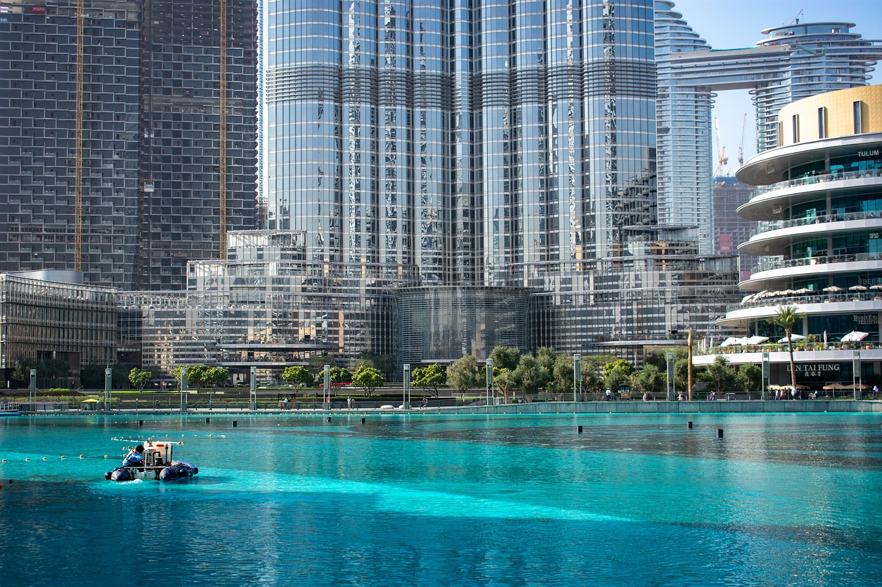 A stunning daytime view of Burj Khalifa with reflections on its glass facade, overlooking a vibrant turquoise water body in Dubai.